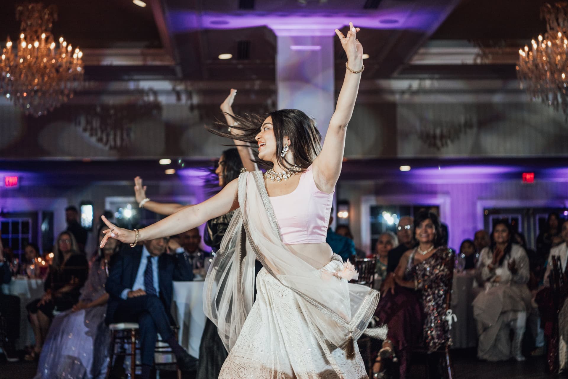 A guest dancing joyfully on the reception floor under chandelier light