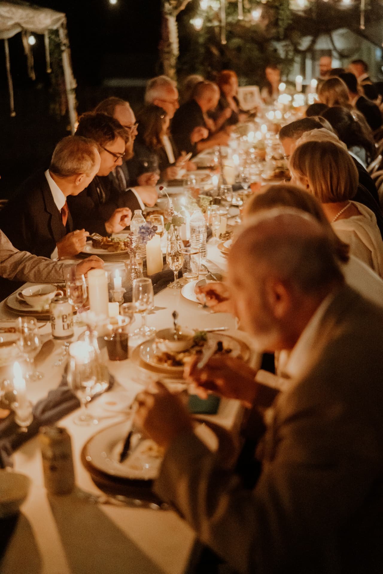 Guests dining along a candlelit banquet table on the wedding night