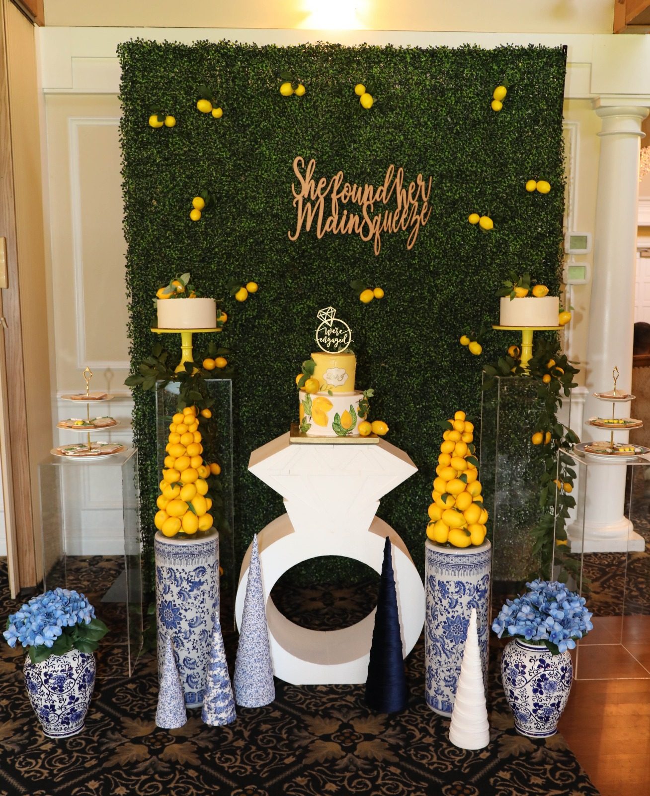 A lemon themed dessert table against a hedge wall